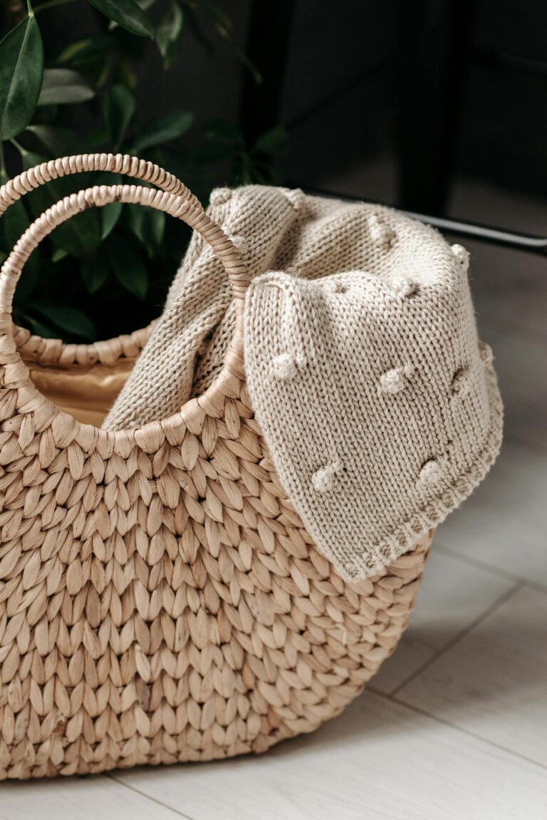 A detailed close-up of a handwoven basket with a textured knit blanket indoors.