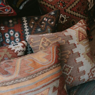 Close-up of vibrant ethnic throw pillows with intricate designs stacked on a sofa.