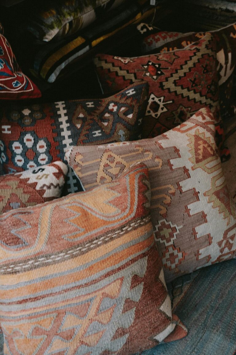 Close-up of vibrant ethnic throw pillows with intricate designs stacked on a sofa.