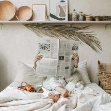 Relaxing in bed with a newspaper and breakfast on a lazy Sunday morning.