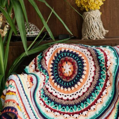Vibrant crochet blanket adding warmth to a cozy indoor setting with plants and decor.